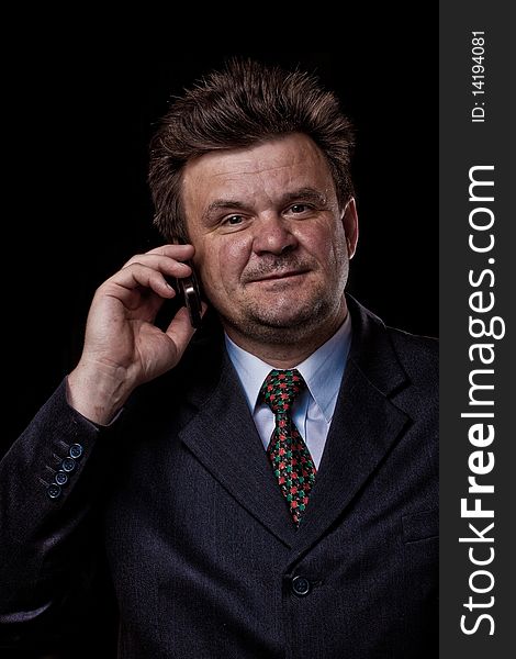 Businessman with mobile phone speaking on black background