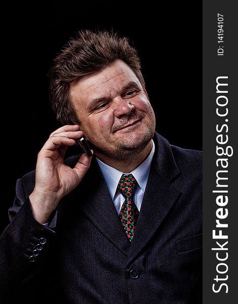 Businessman with mobile phone speaking on black background