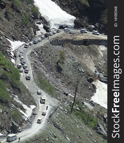 A scene of a steep Himalayan hill road with vehicles.
