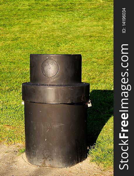 A black litter bin in a park