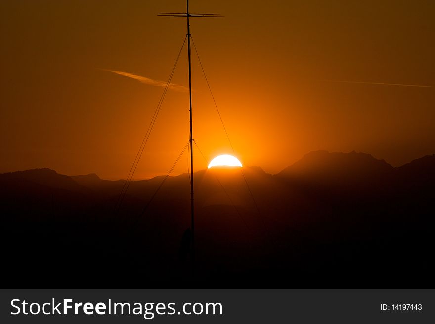 Sunset behind Alps mountains got in Turin over a building roof with Television Antenna. Sunset behind Alps mountains got in Turin over a building roof with Television Antenna