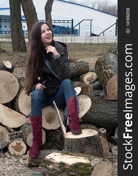 Young beautiful teenage girl sitting on logs