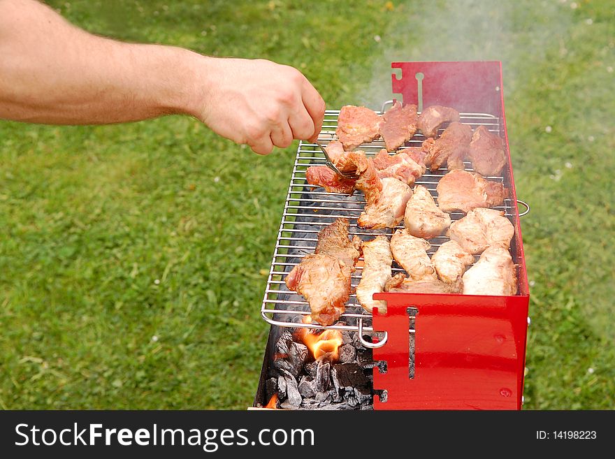 Man turning meat on a barbecue grill