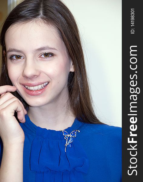 Portrait of beautiful smiling teenage girl in a blue dress with a brooch. Portrait of beautiful smiling teenage girl in a blue dress with a brooch