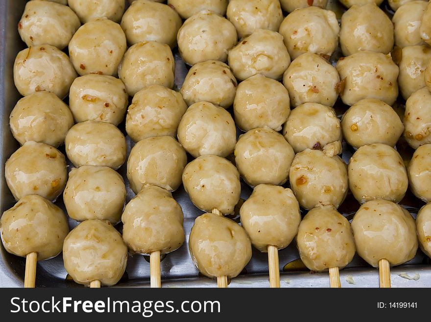 Meatballs on sticks, dipped in sweet chili sauce at a market in Thailand