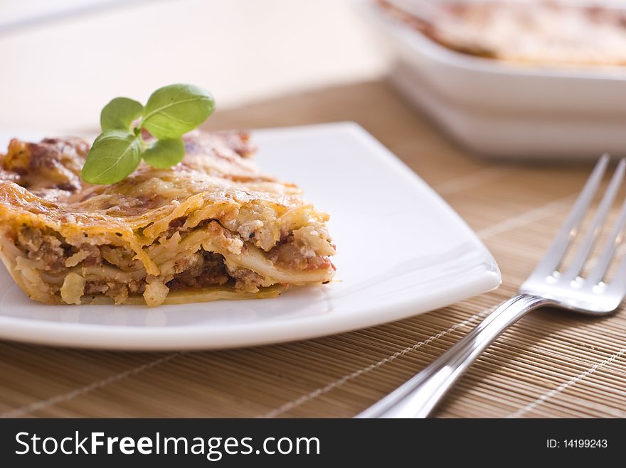 Lasagna on white plate with basil