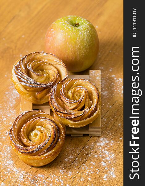 Tasty Apple Rose mini tarts with icing sugar and cinnamon on wooden background. Tasty Apple Rose mini tarts with icing sugar and cinnamon on wooden background