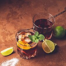 Cocktail Of Rum And Cola Ice Cubes And Lime In Glass Goblets On A Dark Brown Background. Strong Alcoholic Drink. Stock Image