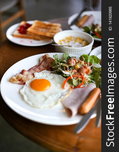 Healthy breakfast spread on a table with coffee, orange juice, fruit, muesli, smoked salmon, egg, croissants, meat and cheese