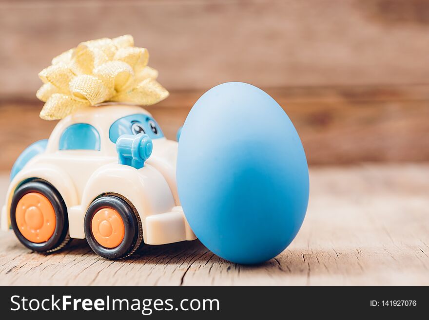 Easter egg and toy car on wooden background, happy easter day concept