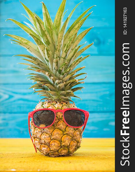 Holiday pineapple have sunglasses on blue wooden background