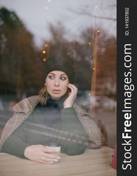 Young beautiful woman wearing fashion clothes sitting in a cafe drinking coffee