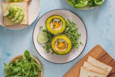 Healthy Vegan Breakfast. Diet. Baked Avocado With Egg And Fresh Salad From Arugula, Toast And Butter. On A White Marble Plate, A Stock Photo