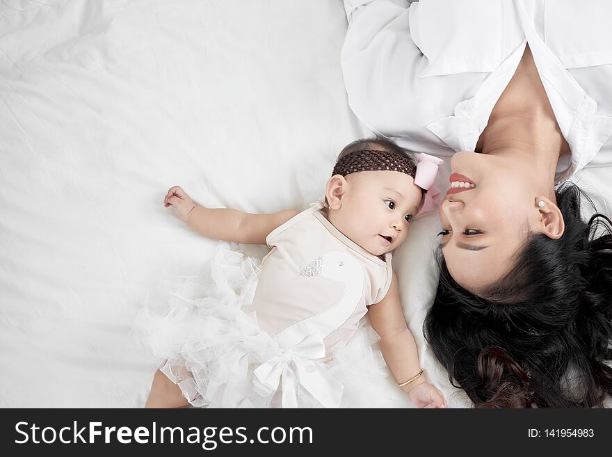 Cute Little Baby Girl And Her Mother Lying On A Floor