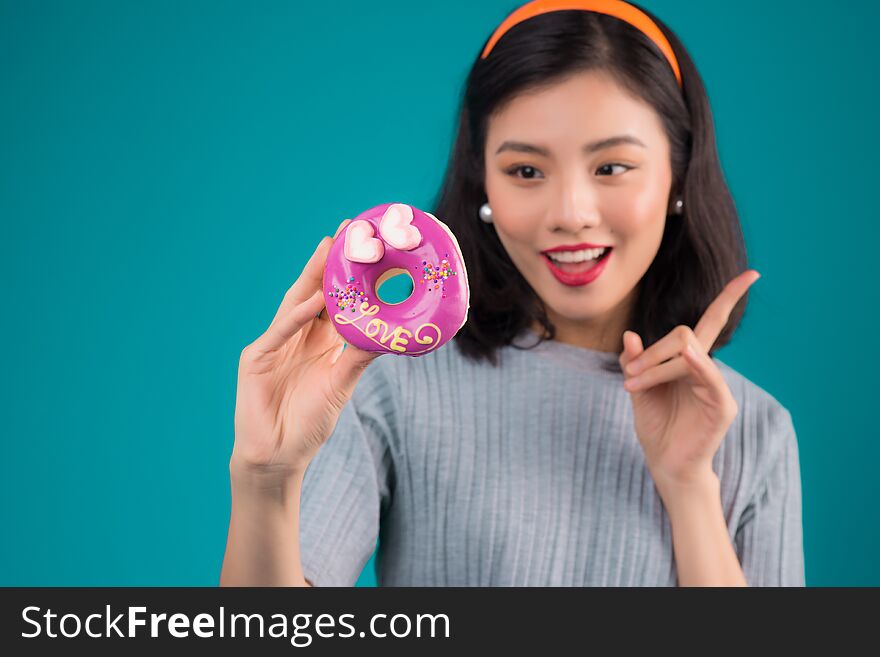 Asian beauty girl holding pink donut. Retro joyful woman with sweets, dessert standing over blue background