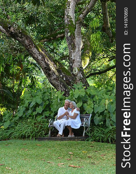 Happy elderly couple in tropical garden sitting on bench ,outdoor. Happy elderly couple in tropical garden sitting on bench ,outdoor