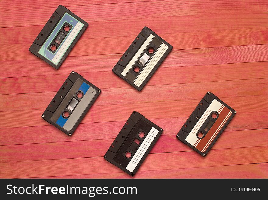 Audio cassettes tape group lay on pink wooden plank composition. Audio cassettes tape group lay on pink wooden plank composition