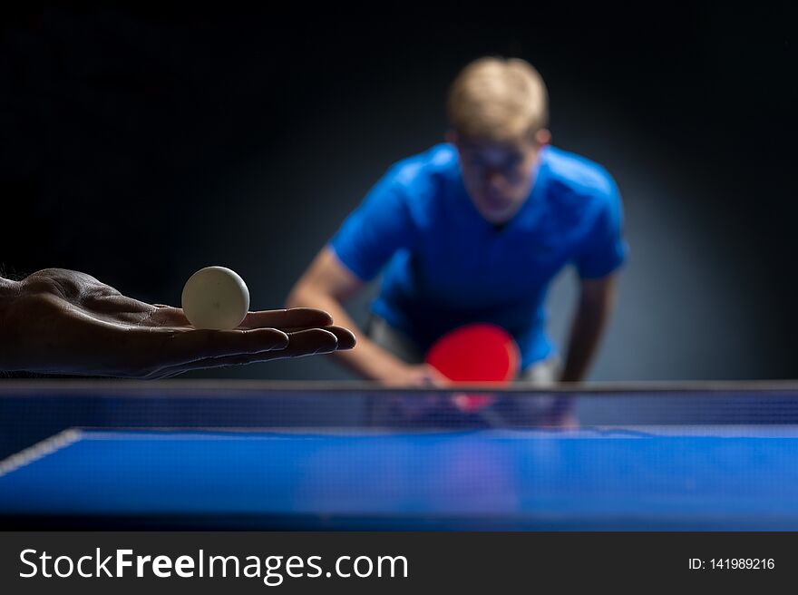 Portrait of young man playing tennis on black background