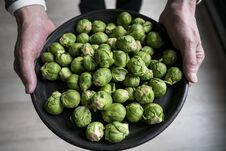 Man Shows Brussels Sprouts On Black Plate Stock Photos