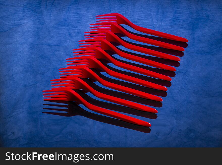 Abstract still life with red forks on blue table