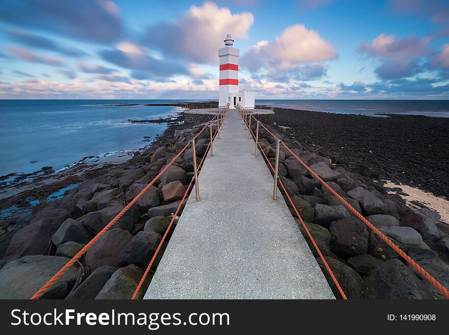 Old Lighthouse In Gardur, Keflavik, Iceland. Cloudy Sky And Choppy Sea. Beautiful Sunset. Golden Circle, Most Popular Place.