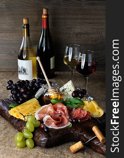 Antipasto catering platter with jerky bacon, prosciutto, salami, cheese and grapes on a wooden background. Antipasto catering platter with jerky bacon, prosciutto, salami, cheese and grapes on a wooden background