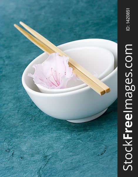 Chinese rice bowls against a textured background with a single azalea flower for styling. Chinese rice bowls against a textured background with a single azalea flower for styling.