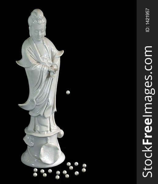 White porcelain Chinese female figure with pearls at her feet and one pearl suspended in the air isolated on black background. White porcelain Chinese female figure with pearls at her feet and one pearl suspended in the air isolated on black background