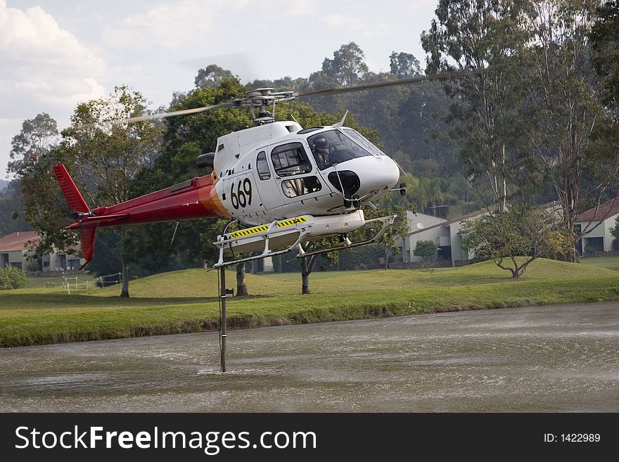 Fire fighting helicopter taking water from golf course. Fire fighting helicopter taking water from golf course