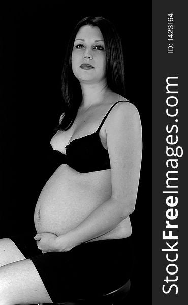 A pregnant lady shot on black.  Expression is of concern