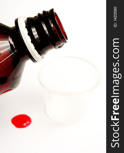 Measuring cough syrup with spilled drop on white background. Measuring cough syrup with spilled drop on white background