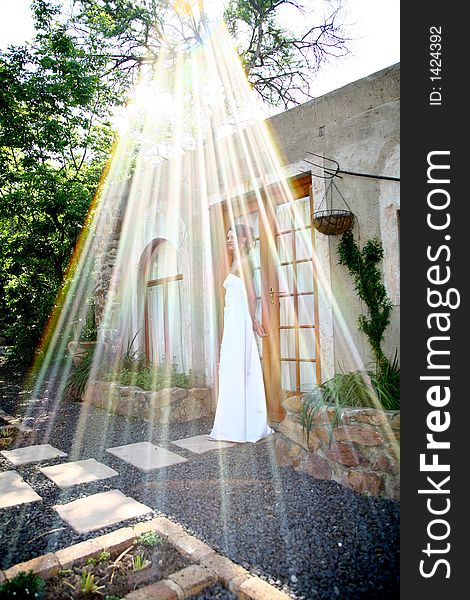 A bride standing outside and sunrays shining down on her. A bride standing outside and sunrays shining down on her
