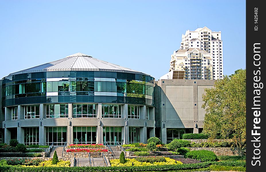 A short round office building next to a tall modern tower. A short round office building next to a tall modern tower