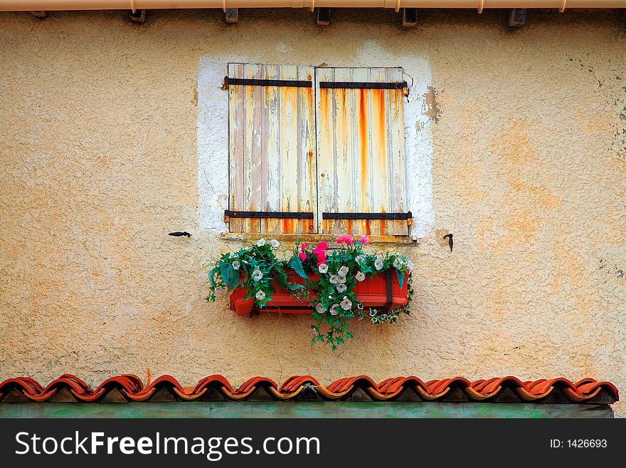 Old white and yellow shutters with rusted stains and pot plants. Old white and yellow shutters with rusted stains and pot plants