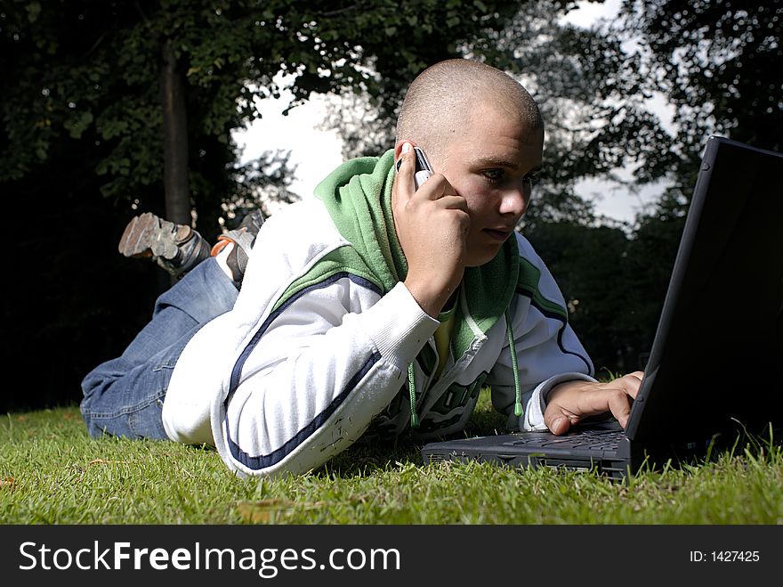 Boy with notebook and cell phone in park