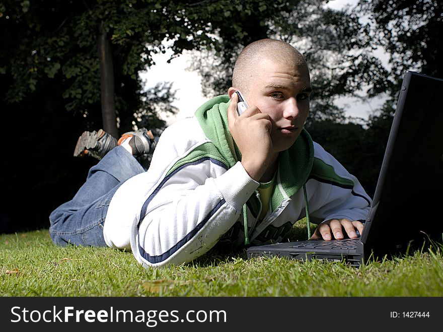 Boy with notebook and cell phone in park
