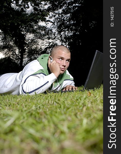 Picture of boy with notebook and cell phone in park