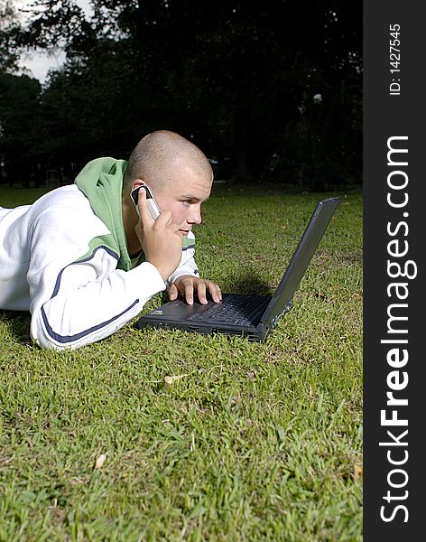 Picture of boy with notebook and cell phone in park