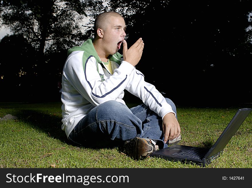 Yawning boy with notebook in park