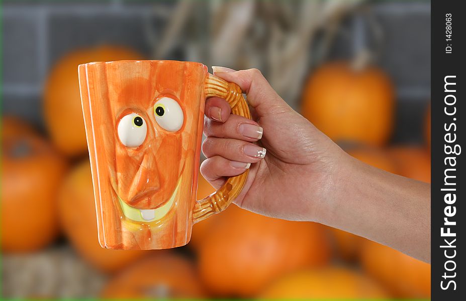 A woman holding a pumpkin shaped coffee mug. A woman holding a pumpkin shaped coffee mug