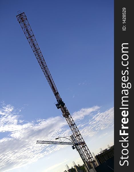 Construction cranes against a cloudy blue sky background