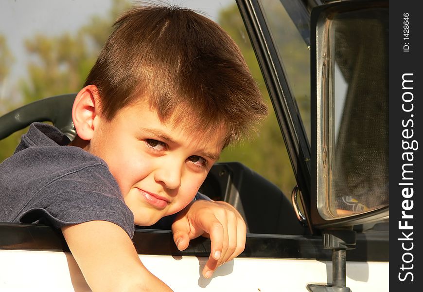A boy sitting in the drivers seat of a vehicle. A boy sitting in the drivers seat of a vehicle