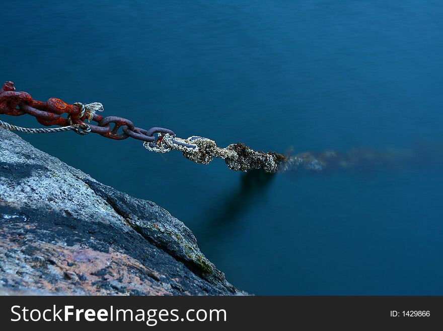 Old boat rusted chains plunging in the depths of the sea
