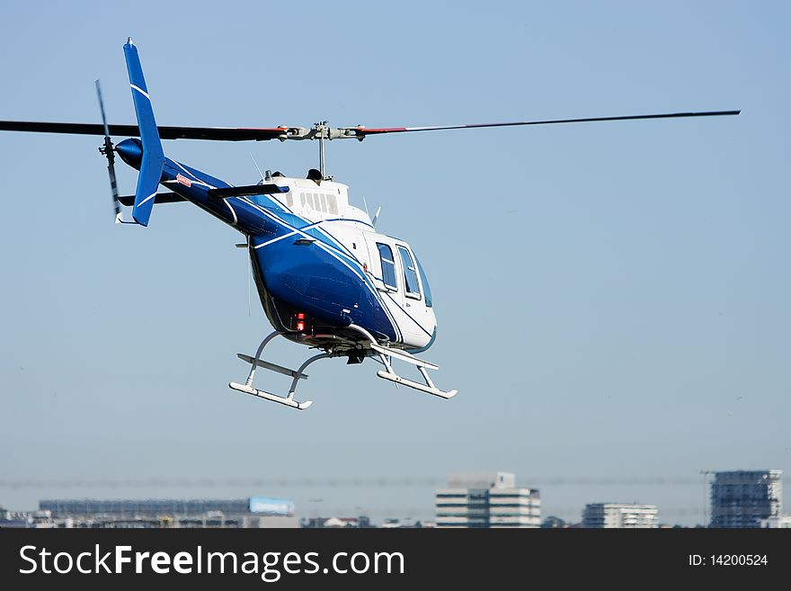 View of blue & white helicopter in flight, from behind. View of blue & white helicopter in flight, from behind.