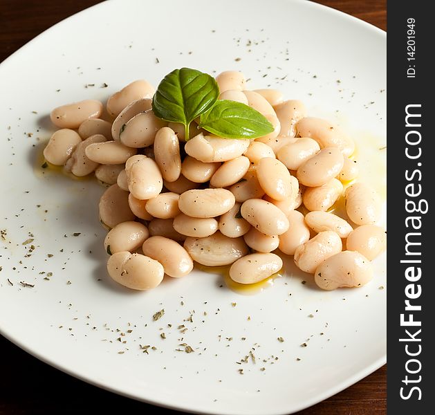 Photo of spanish beans on a white plate with a basil leaf