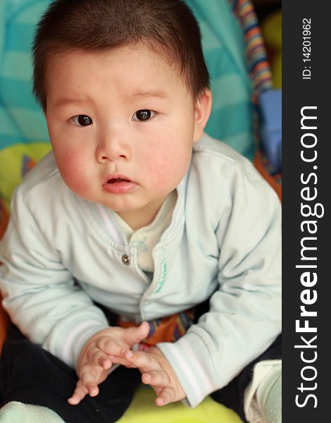 Lovely Chinese baby is sitting on a chair