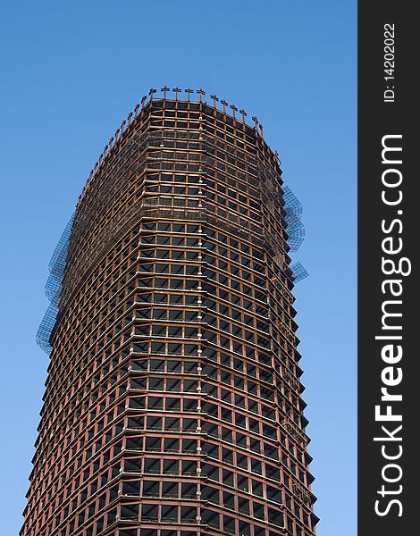 Skyscraper with scaffolding over clear blue sky. Skyscraper with scaffolding over clear blue sky