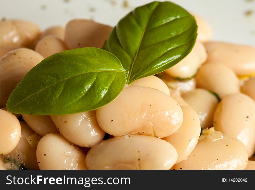 Photo of spanish beans on a white plate with a basil leaf