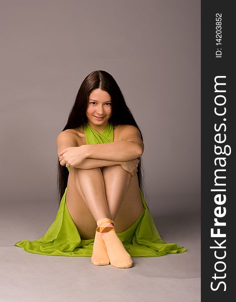 Attractive girl sitting on the floor - gray background