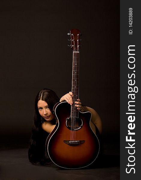 Attractive girl hiding behind a guitar